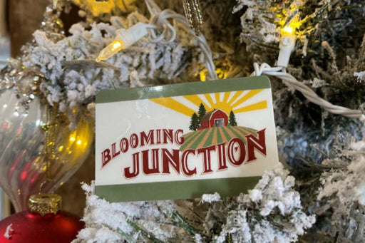 Decorative sign with 'Blooming Junction' on a Christmas tree with lights and ornaments.